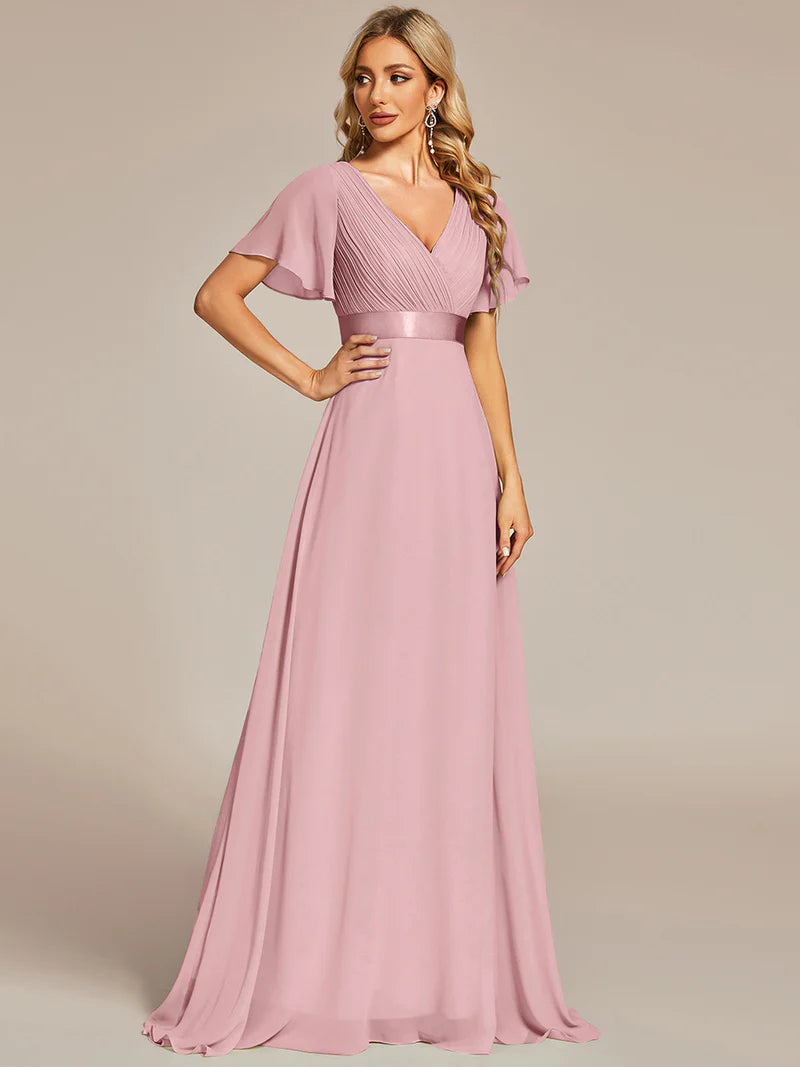 Woman wearing a dusty rose evening gown against a plain background