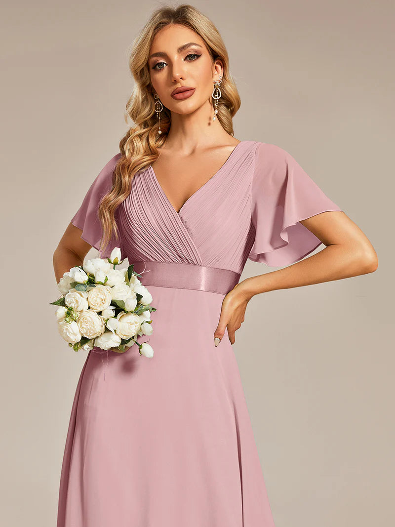 Woman in a dusty dress holding a bouquet of flowers against a beige background