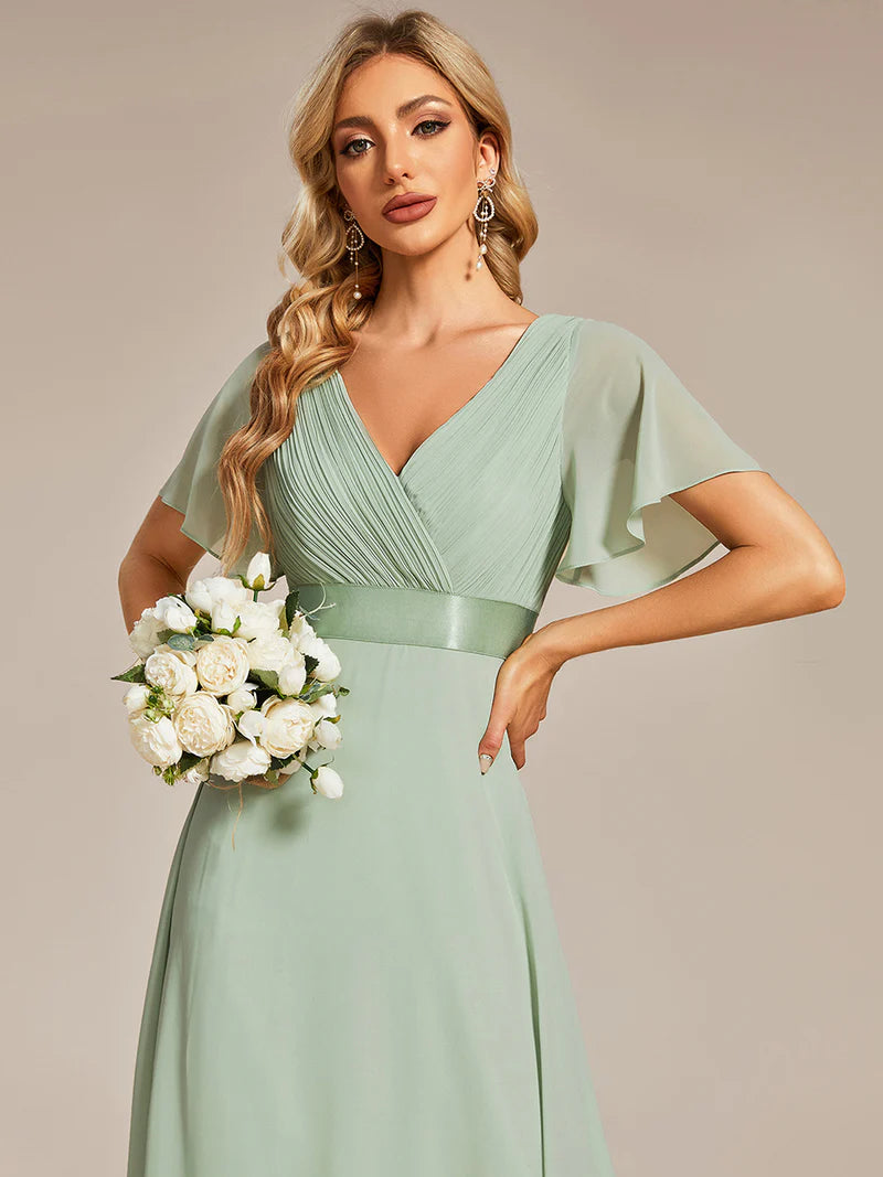 Woman in a mint green dress holding a bouquet of white flowers against a beige background
