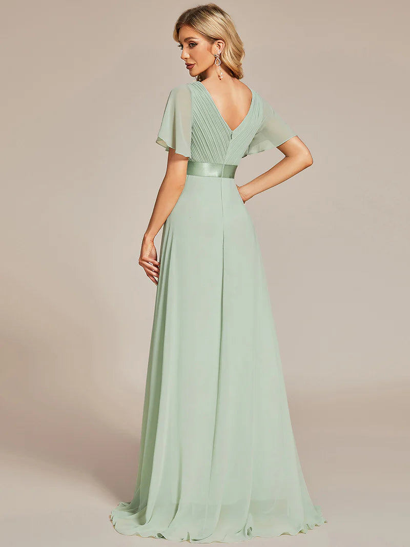 Woman wearing a mint green evening gown with a belt on a beige background