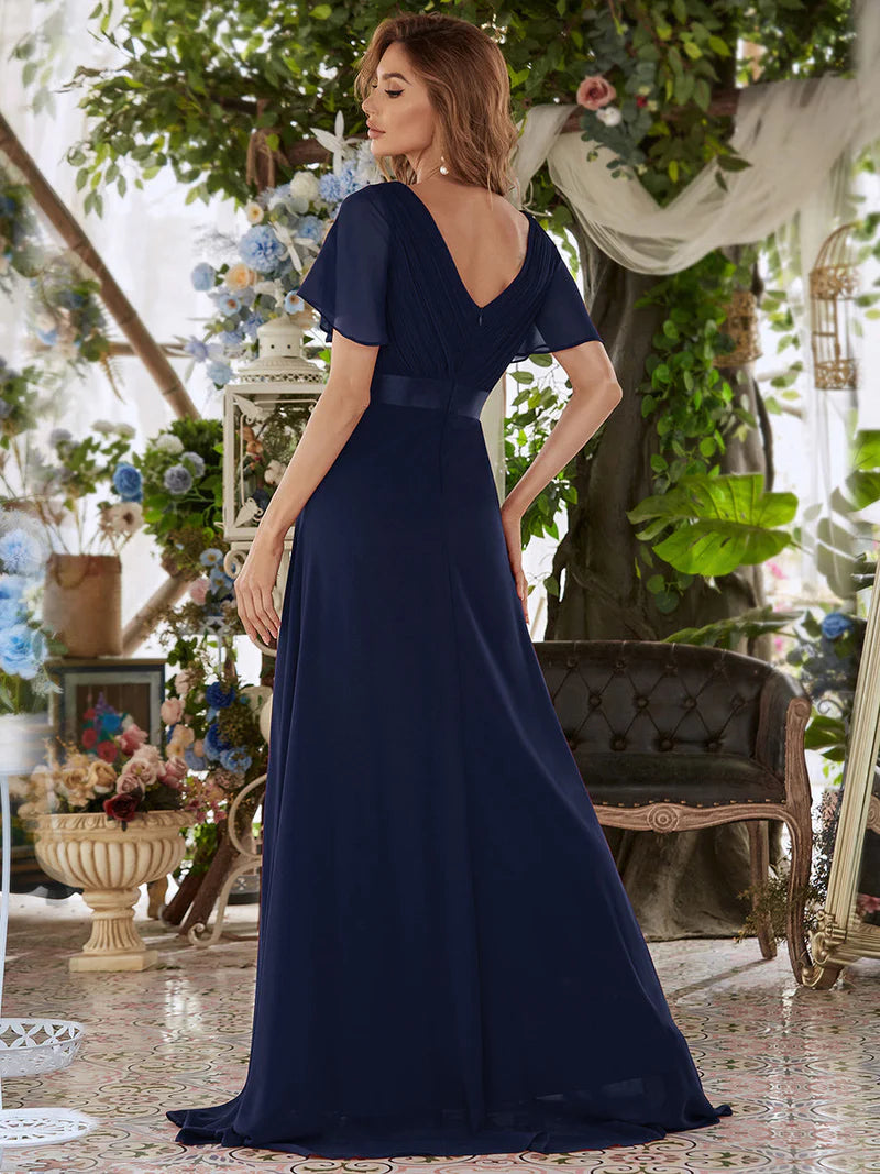 Woman wearing a navy blue evening gown in an elegant indoor setting with floral decorations.