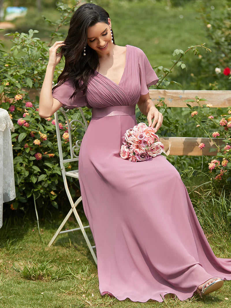 Woman in a long orchid dress holding a floral clutch in a garden setting