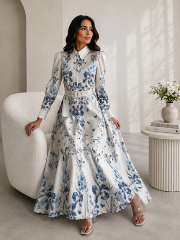 Woman in a floral dress sitting on a white chair in a modern interior setting.