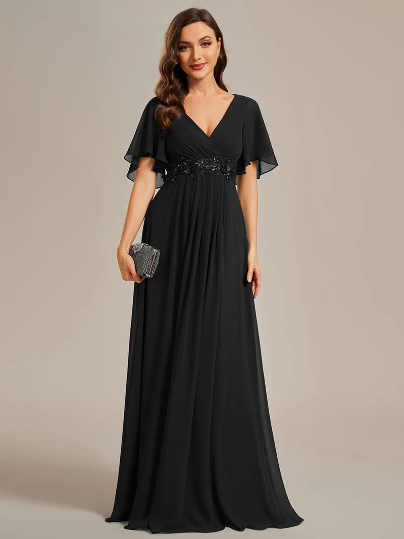 Elegant black bridesmaid dress with V-neckline, pleated skirt, and floral appliqués