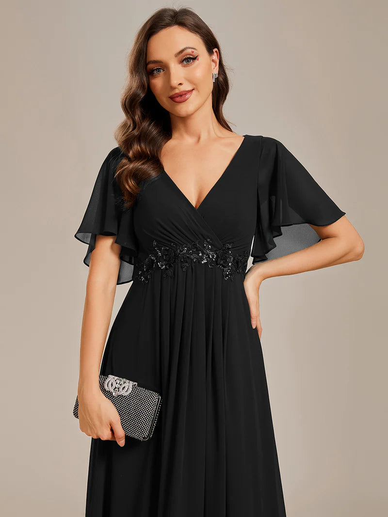 Elegant black bridesmaid dress with V-neckline, pleated skirt, and floral appliqués