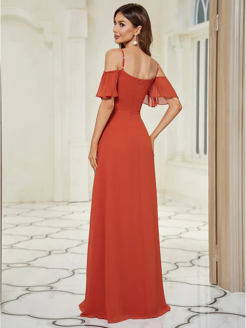 Woman wearing a burn orange off-shoulder evening gown in an elegant interior setting