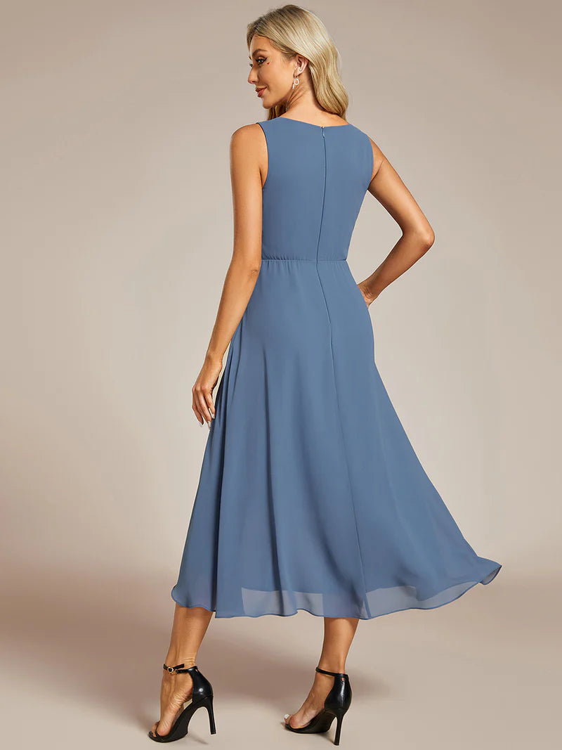 Dusty blue tea-length chiffon wedding guest dress with V-neckline and delicate appliqués