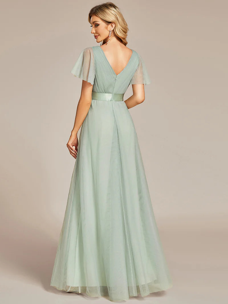 Mint green evening gown with sheer sleeves on a beige background