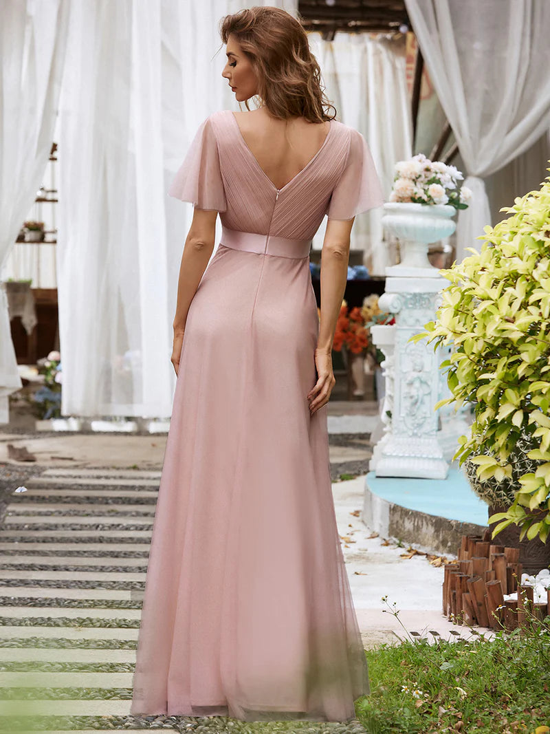 Woman in a pink dress standing outdoors with decorative elements in the background