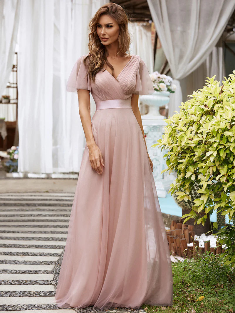 Woman in a pink dress standing outdoors with decorative elements in the background