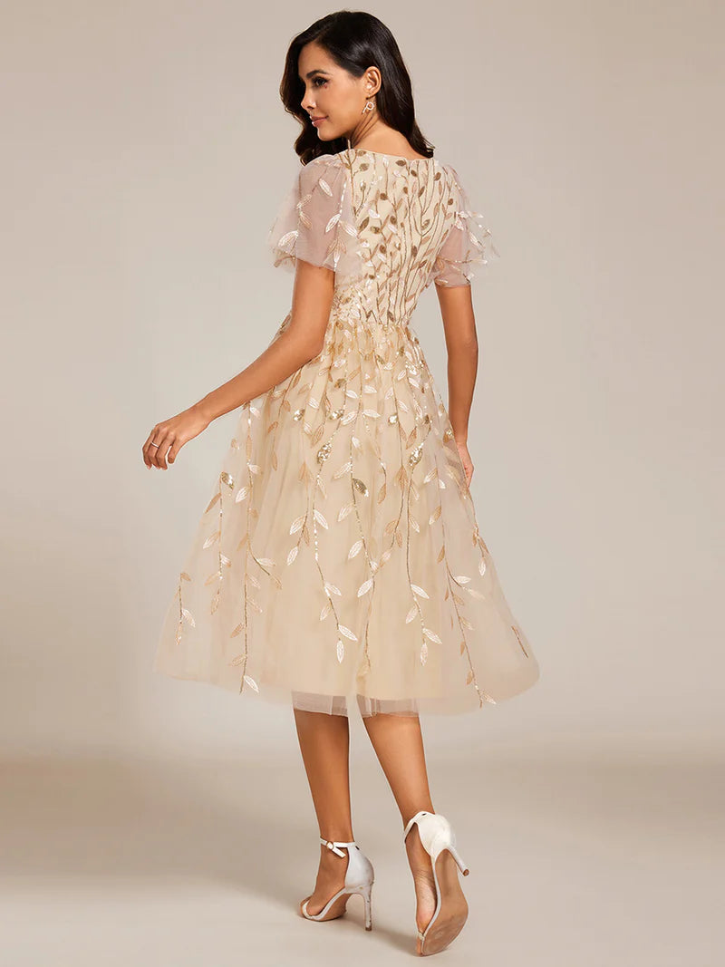 Exquisite midi length gold dress with ruffled sleeves, tulle fabric, sequin details, and embroidery