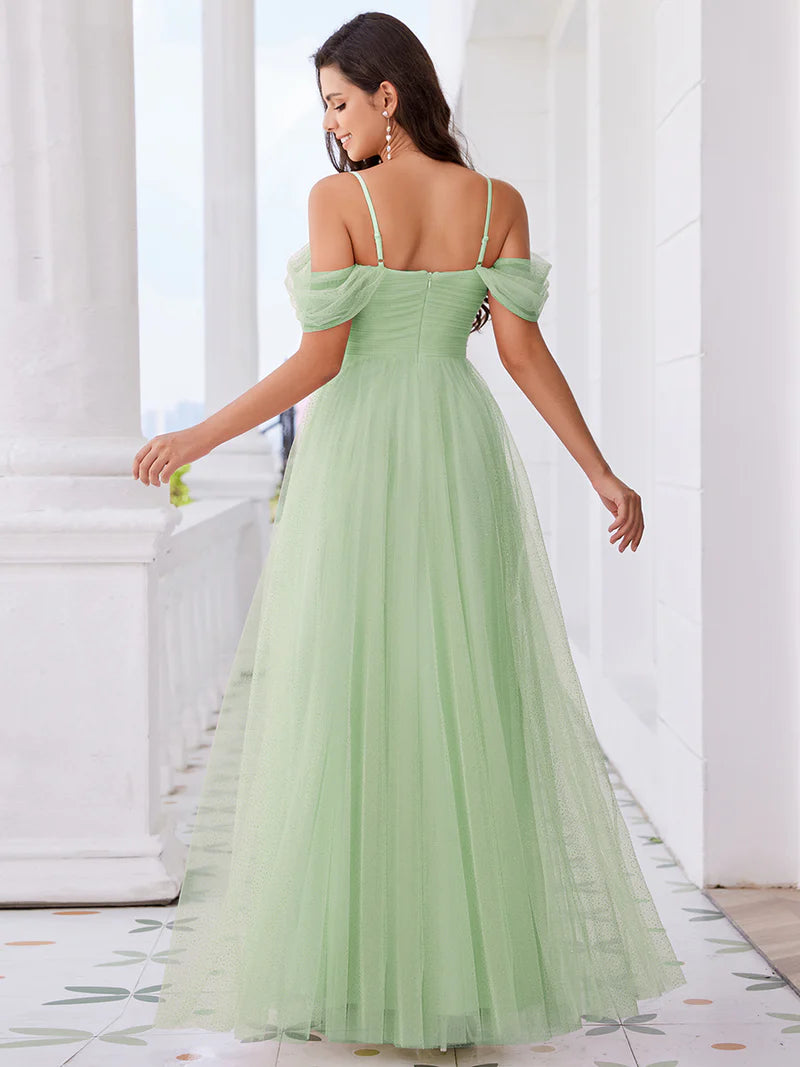 Woman wearing a mint green off-shoulder dress in an elegant interior setting
