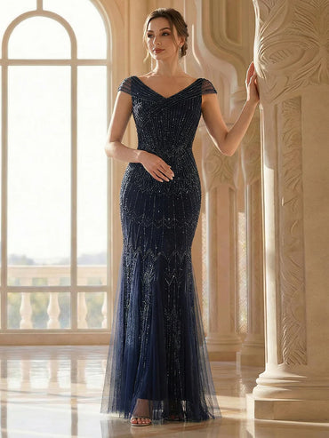 Woman in a navy blue evening gown standing in an elegant interior setting.