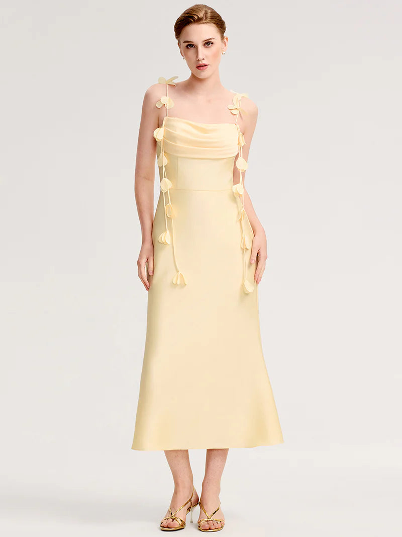 Woman wearing a yellow two shoulder dress with floral details on a white background