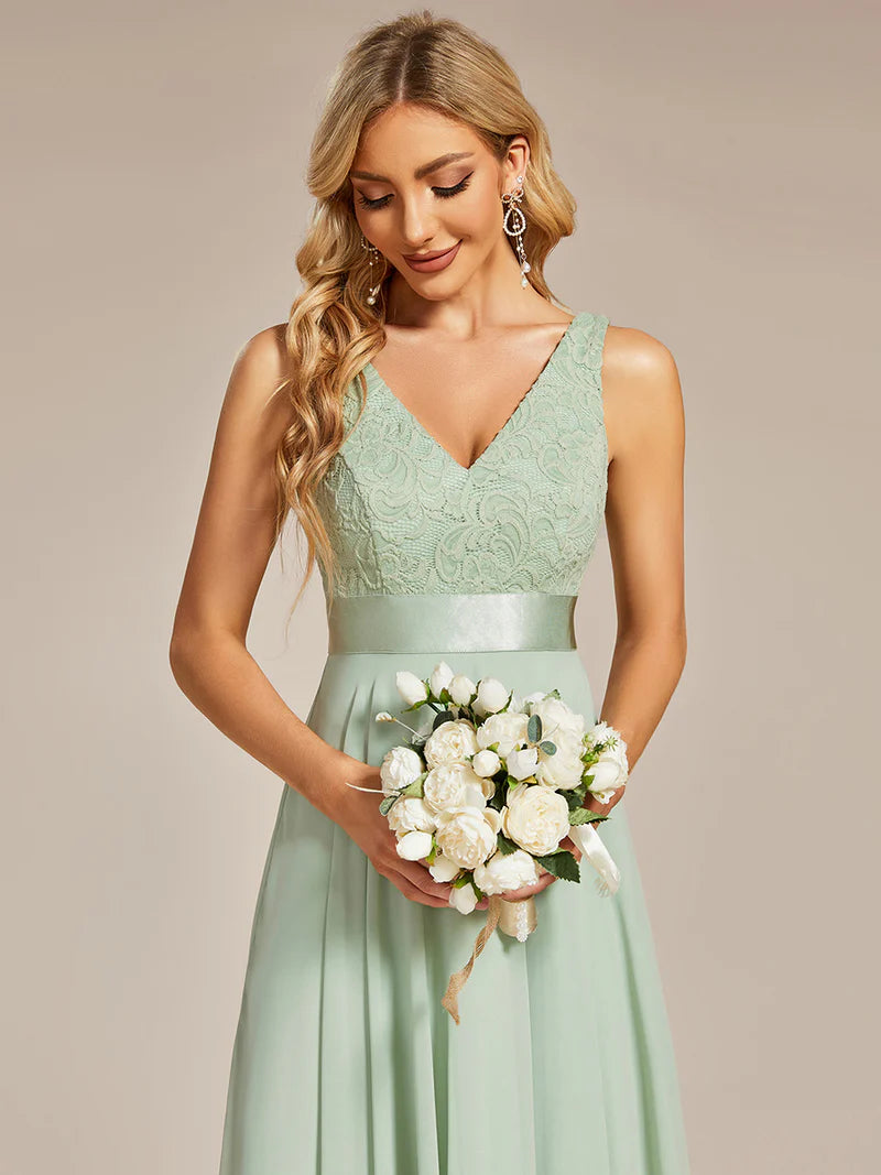 Woman in a lmint green dress holding a bouquet of flowers against a beige background