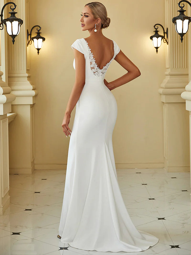 White wedding dress with deep V-neckline, backless design, fishtail silhouette, and sheer cover sleeves