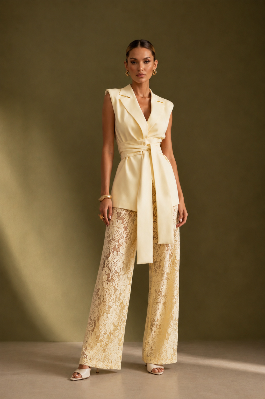 Woman wearing a light-colored sleeveless top and wide-leg pants against a brown background