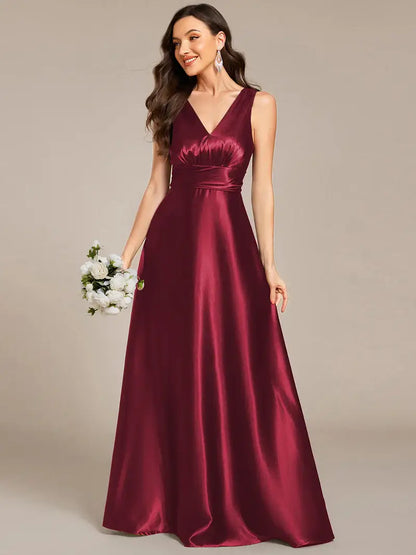 An elegant floor-length satin bridesmaid dress featuring a deep V-neckline and an empire waist. The dress flows gracefully to the floor with a sleek silhouette and includes practical side pockets. The satin fabric gives it a luxurious, polished look, perfect for weddings and formal occasions.