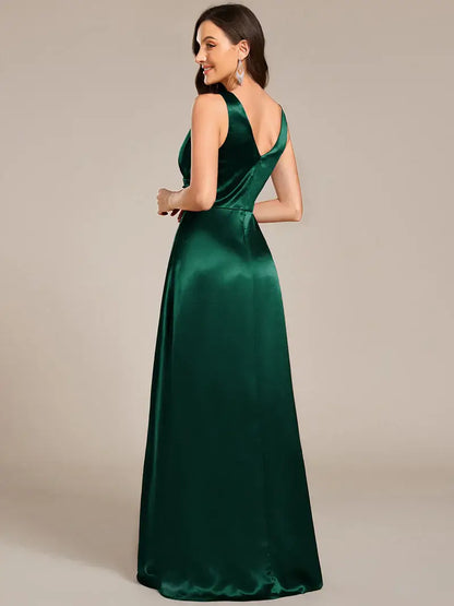 Woman wearing a dark green satin evening gown against a beige background