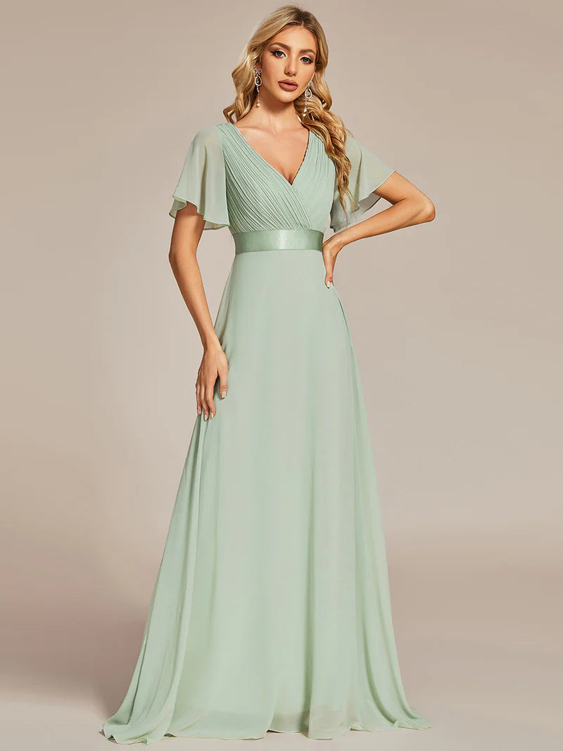 Woman wearing a mint green evening gown against a beige background