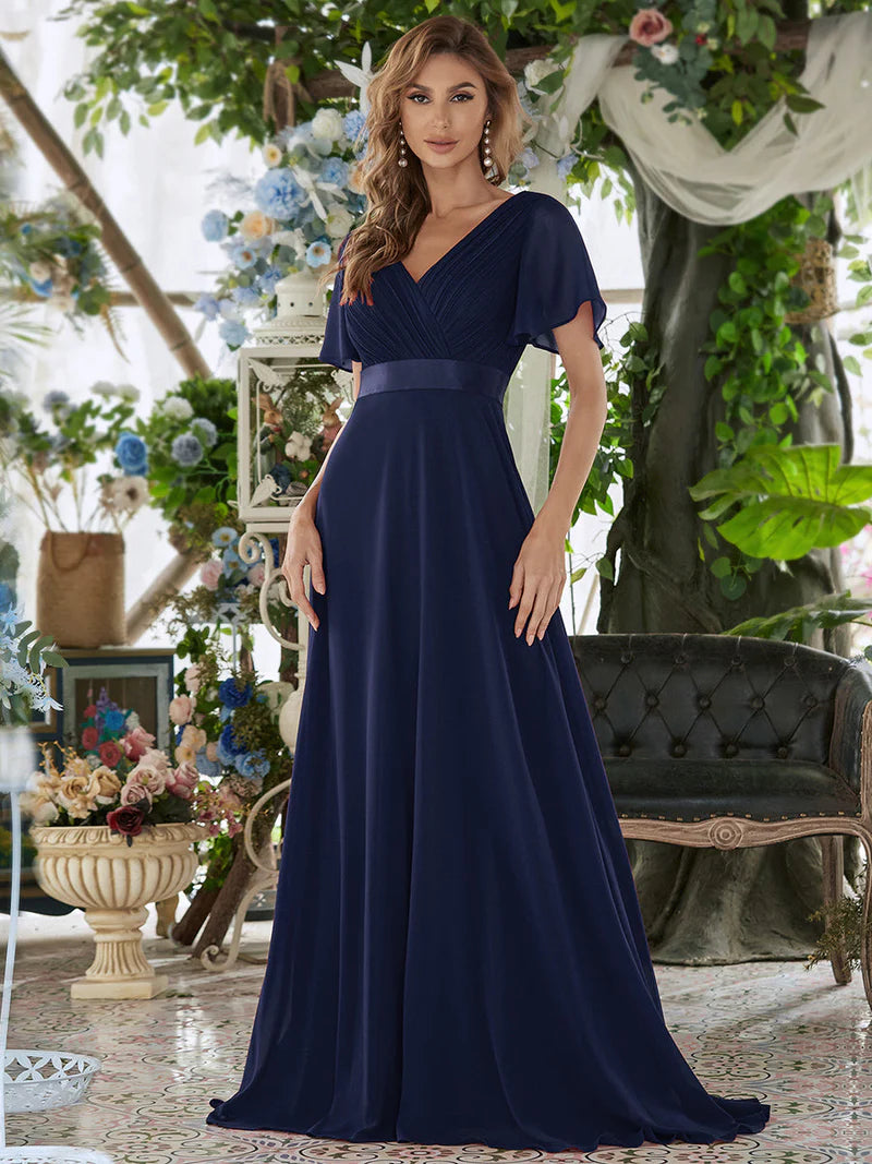 Woman wearing a navy blue dress in an elegant indoor setting with floral decorations.