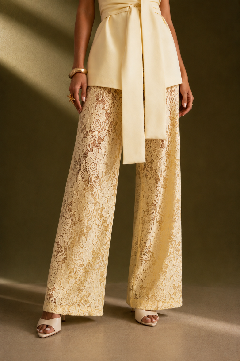 Person wearing a light-colored outfit with a patterned skirt and wide-leg pants on a neutral background