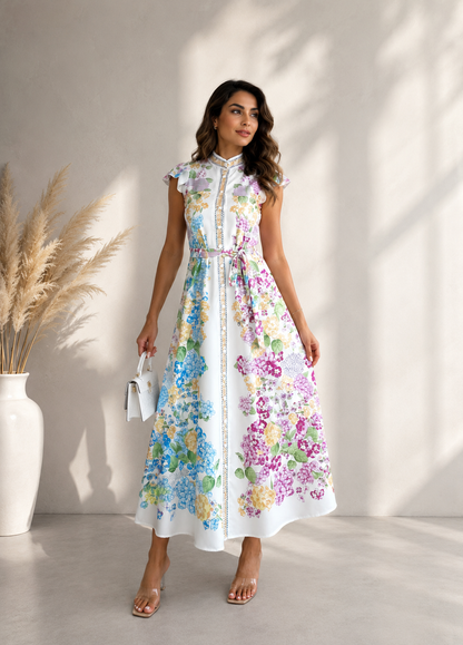 Woman wearing a floral dress standing in a bright room with a vase of pampas grass.