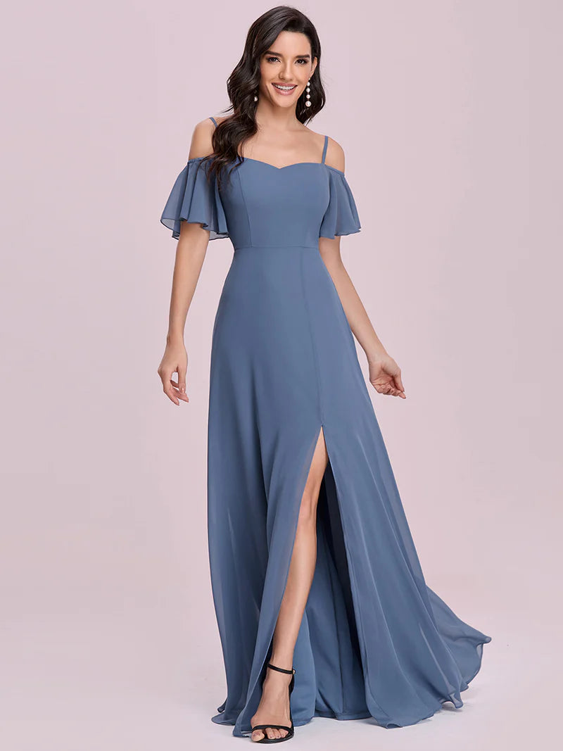 Woman wearing a blue off-shoulder gown with a slit on a light pink background