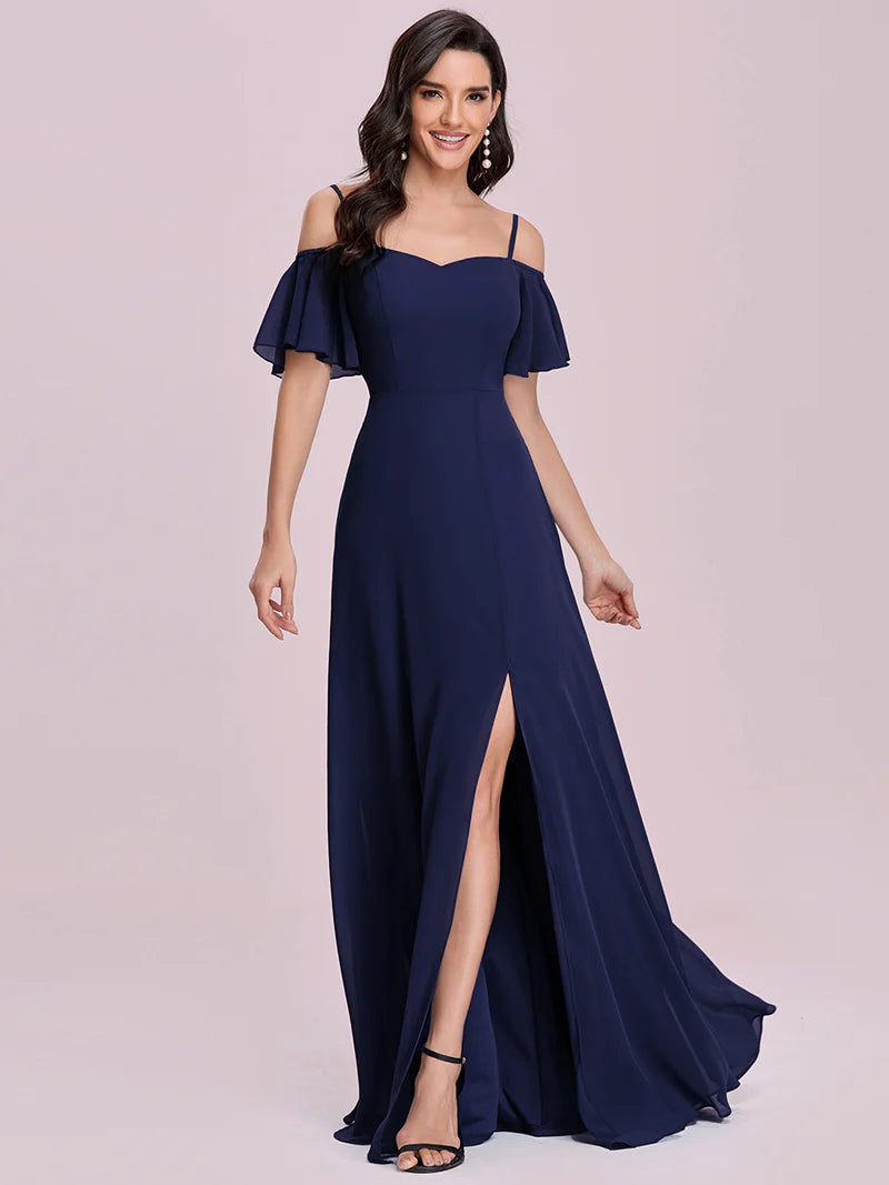 Navy blue off-shoulder gown with a slit on a light pink background