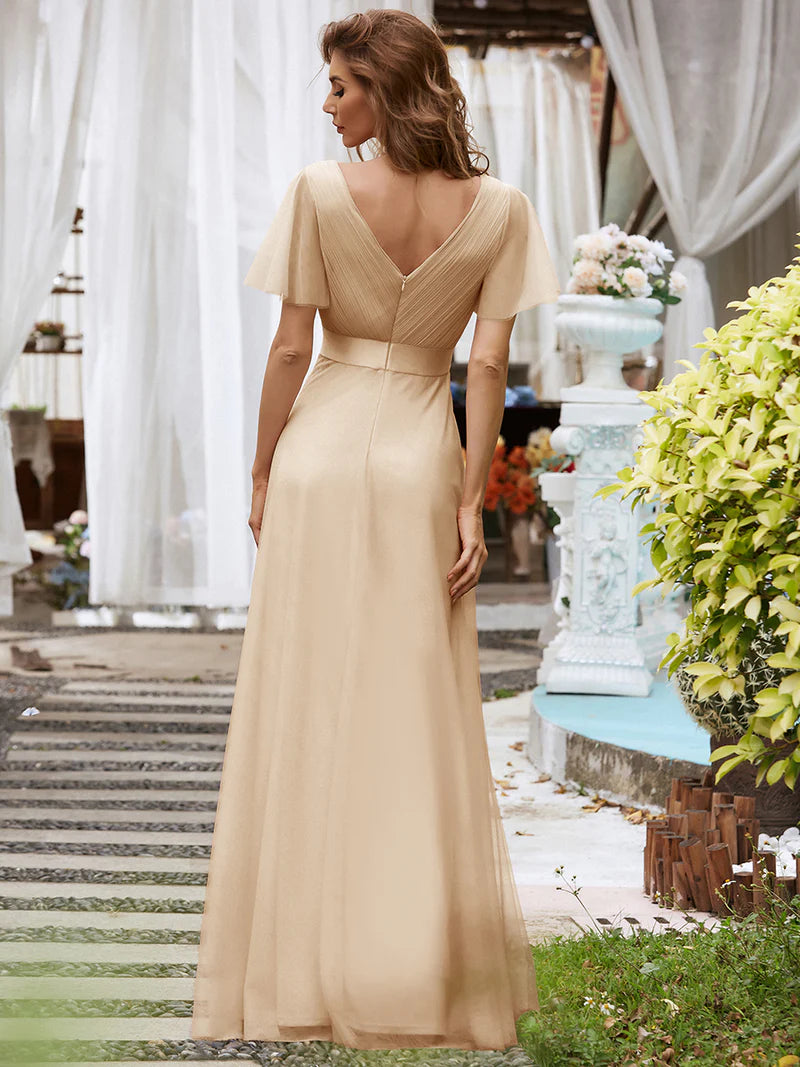 Woman in a Champagne evening gown standing outdoors with decorative elements in the background