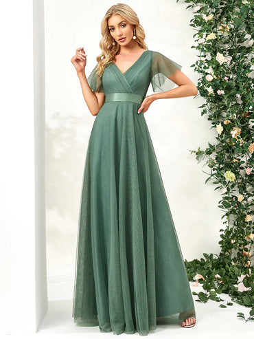 Woman wearing a bean green evening gown with floral decorations in the background