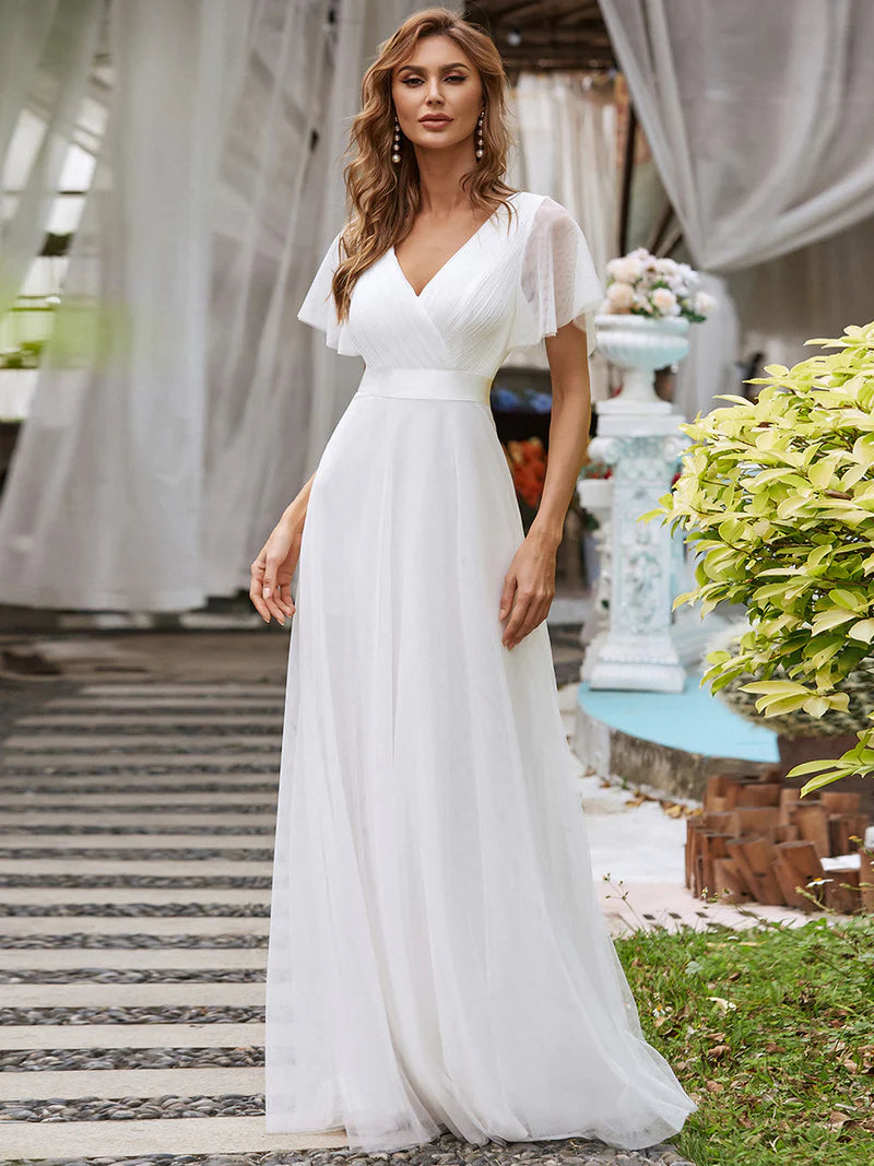 Woman in a white dress standing outdoors with decorative elements in the background