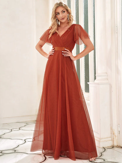 Woman wearing a burnt orange evening gown in an elegant room.
