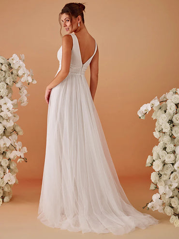 Woman in a ivory wedding dress standing between floral arrangements on a beige background