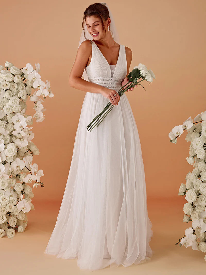 Woman in a ivory wedding dress holding flowers against a beige background with floral decorations.