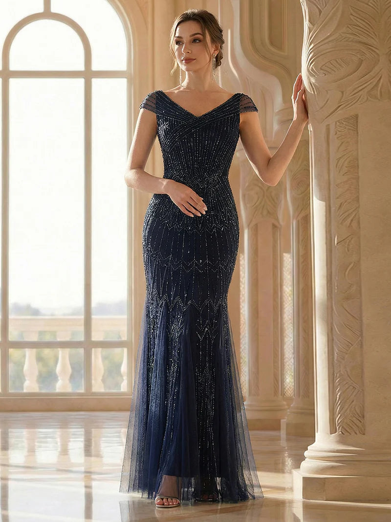 Woman in a navy blue evening gown standing in an elegant interior setting.