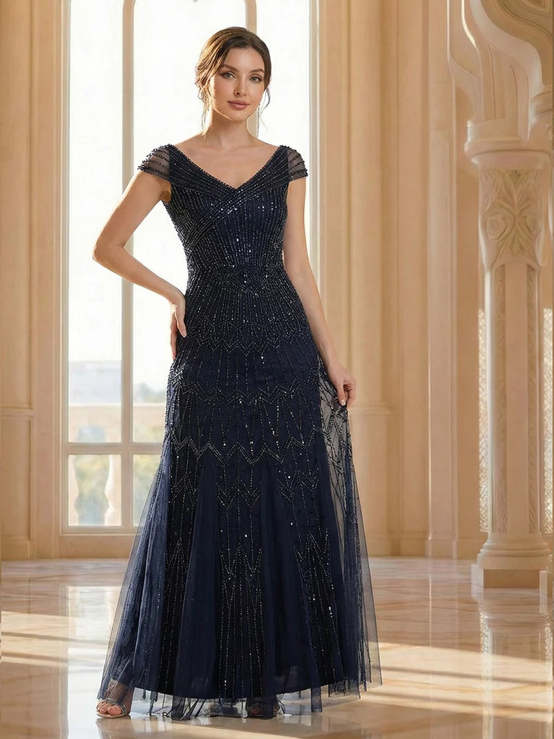 Woman wearing a dark blue beaded evening gown in an elegant interior setting.