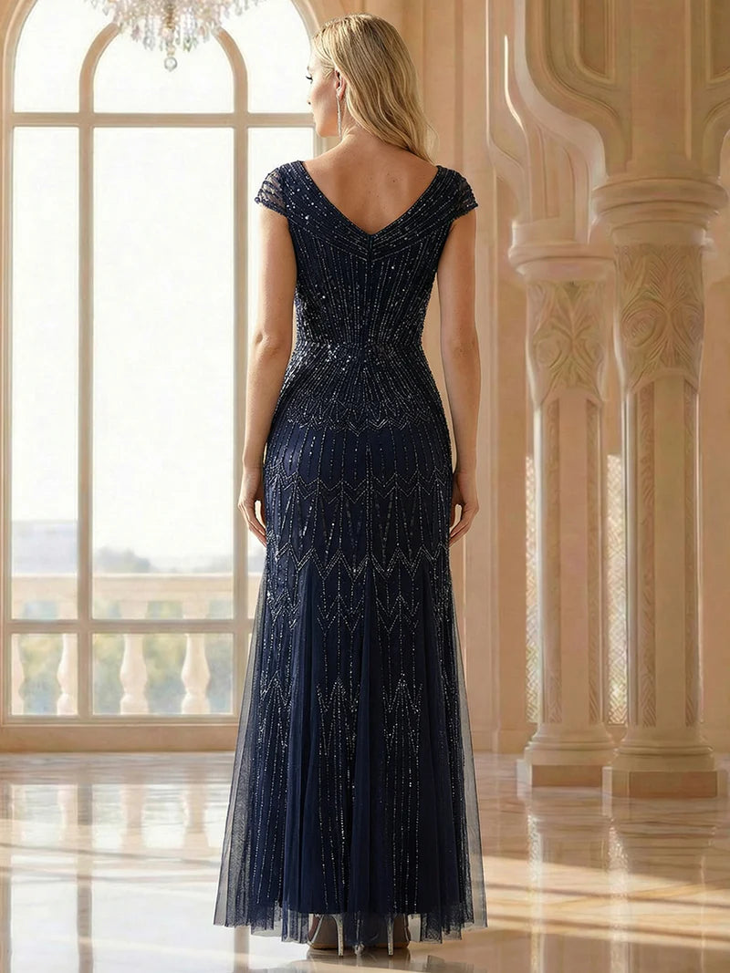 Woman wearing a dark blue evening gown with intricate detailing in a luxurious room.