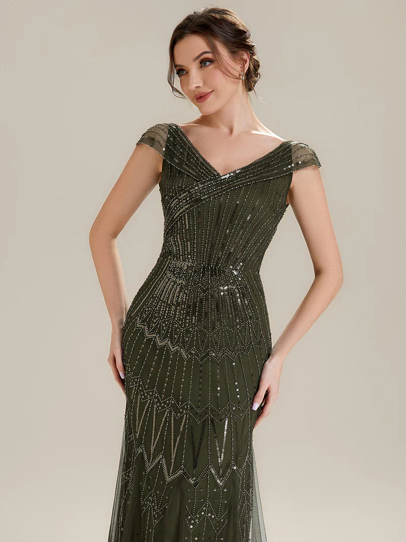 Woman wearing a olive green beaded evening gown against a neutral background
