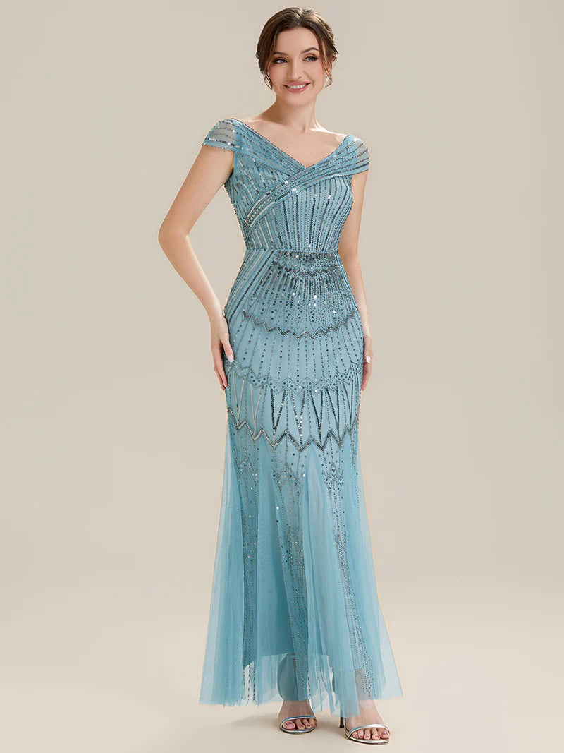Woman wearing a sky blue evening gown with intricate detailing on a neutral background