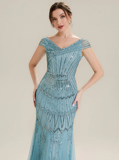 Woman wearing a sky blue beaded evening gown against a beige background