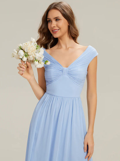 Woman in a sky blue dress holding a bouquet of flowers against a plain background