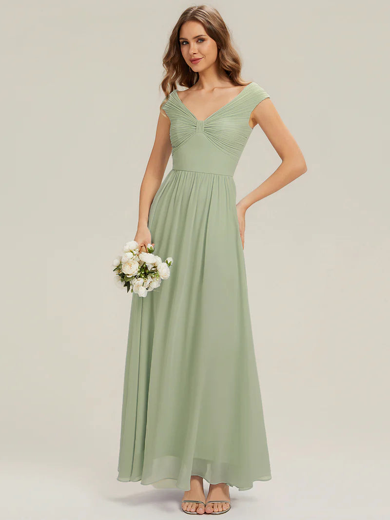 Woman wearing a long mint green dress holding flowers on a plain background