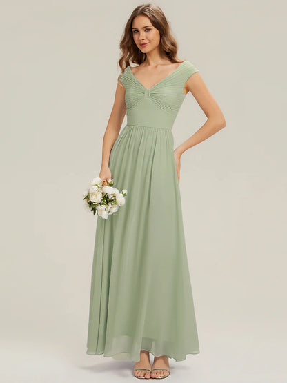 Woman wearing a long mint green dress holding flowers on a plain background