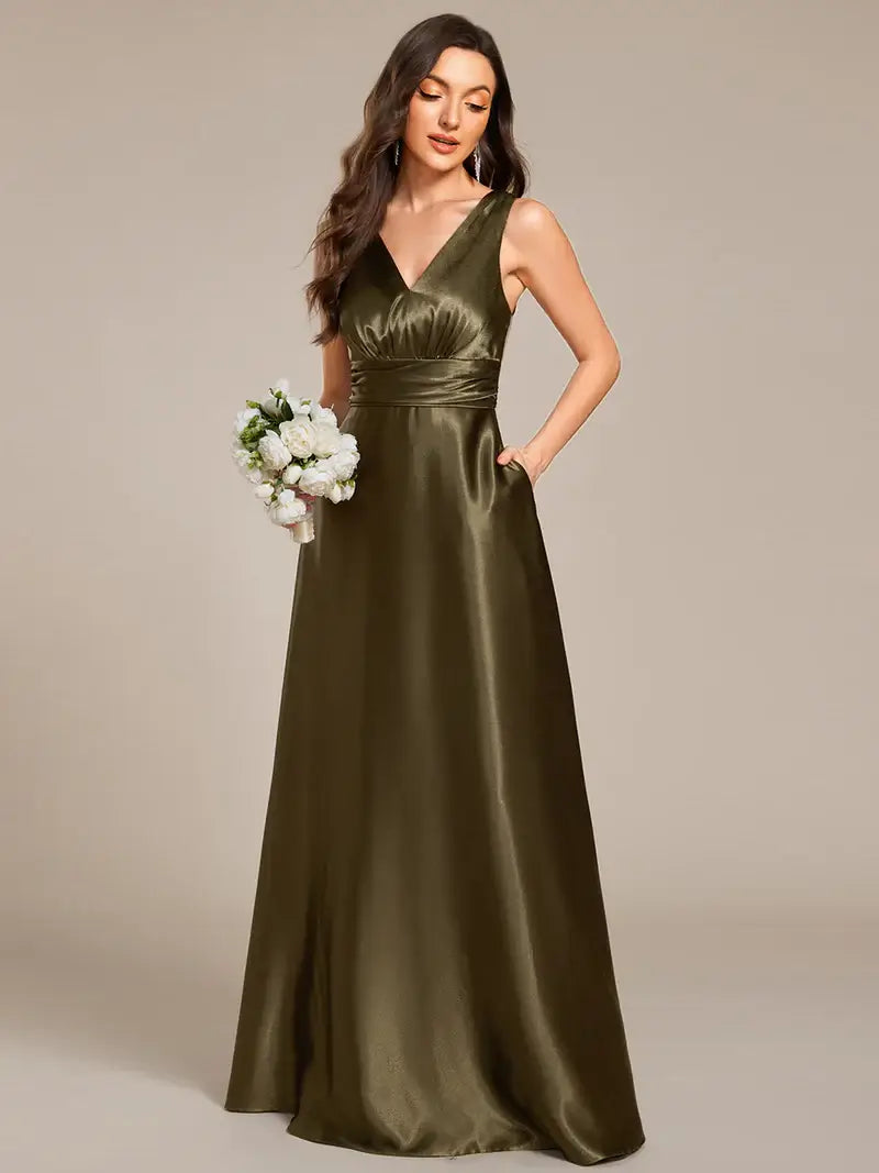 Woman wearing an olive green evening gown holding a bouquet against a beige background