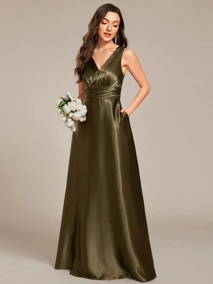 Woman wearing an olive green evening gown holding a bouquet against a beige background