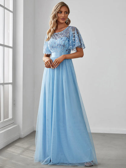 Woman wearing a light blue dress with lace detailing in a room with a window.