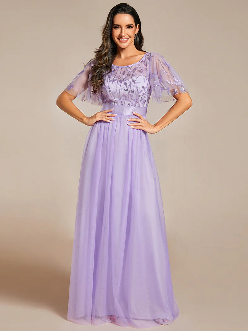 Woman wearing a lavender dress with sheer sleeves against a beige background