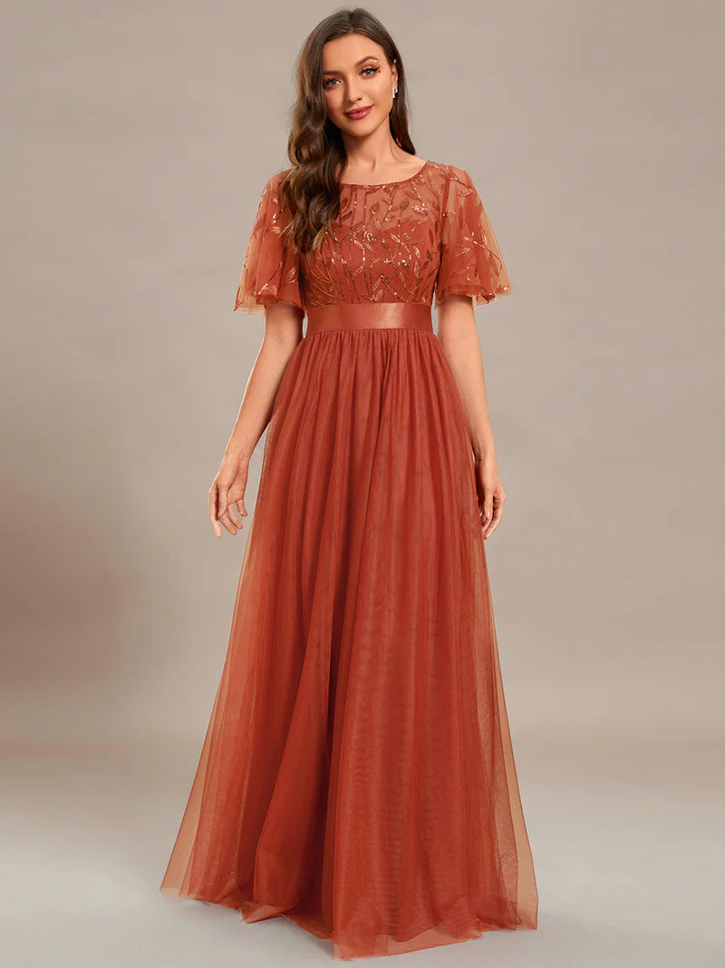 Woman wearing a rburnt orange sequin dress on a plain background