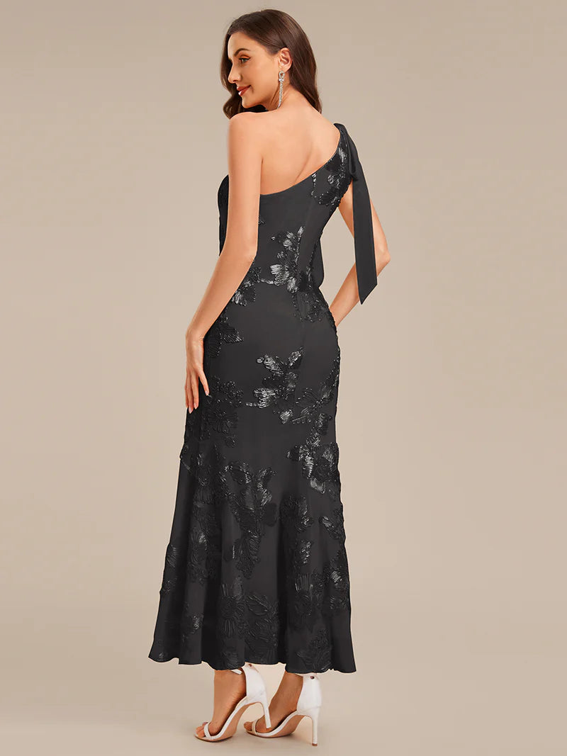 Woman wearing a black lace evening gown on a beige background
